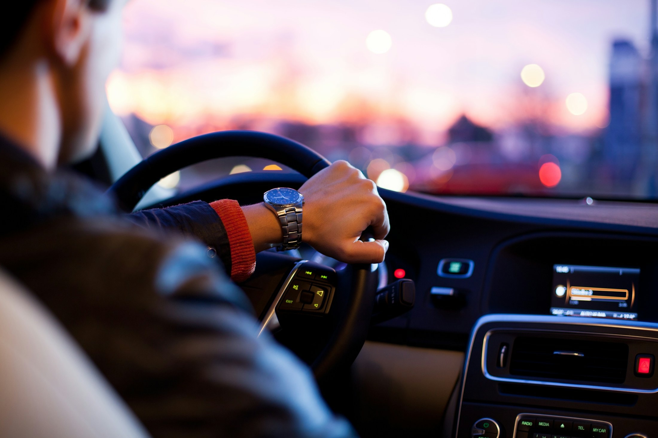 Mãos no volante de um carro ao entardecer