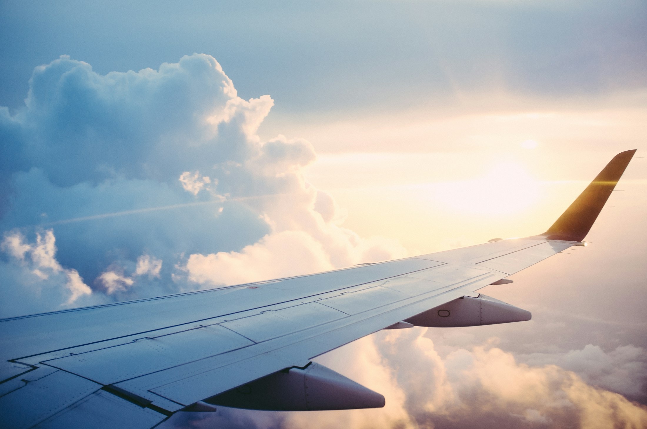 Asa de avião sobre as nuvens ao pôr do sol